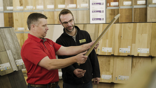 Lumber Liquidators store associate and customer look at a flooring choice in store