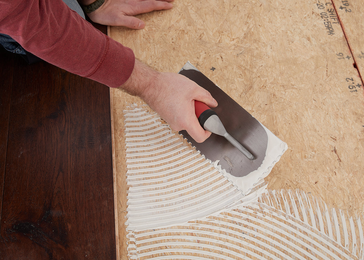 Flooring installer using floor adhesive to install hardwood flooring