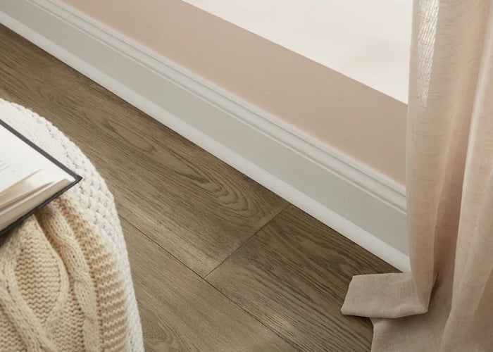 Room with light brown flooring and white baseboard and white shoe molding